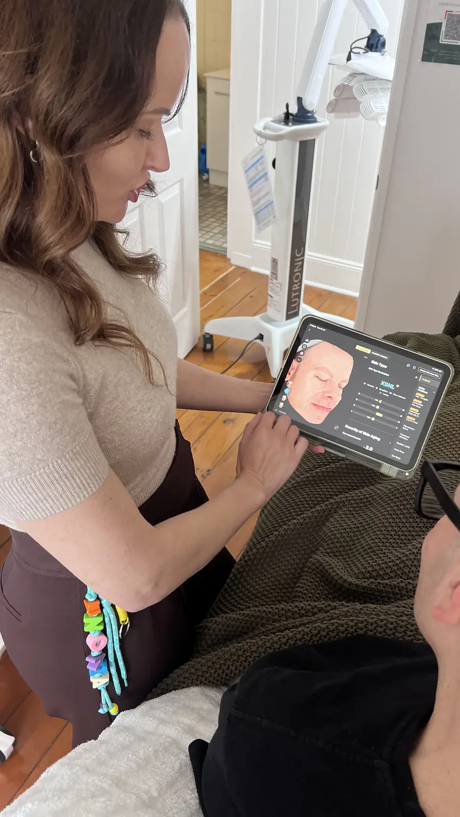 A practitioner reviews a skin analysis on a tablet in the treatment room.